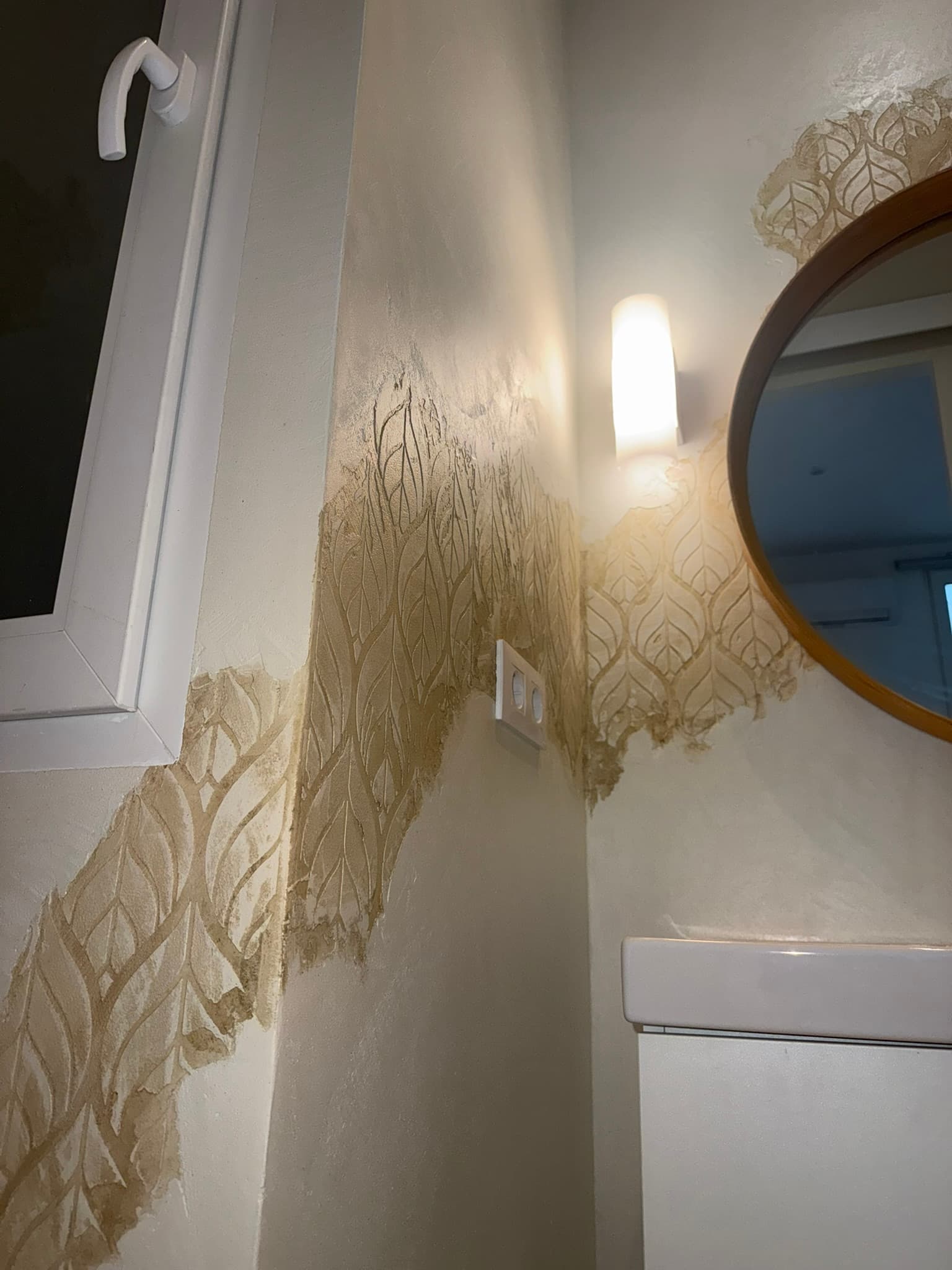 Baño con hornacina de acceso en arco escultórico y pared en estuco liso color crema, junto a bañera y espejo redondo