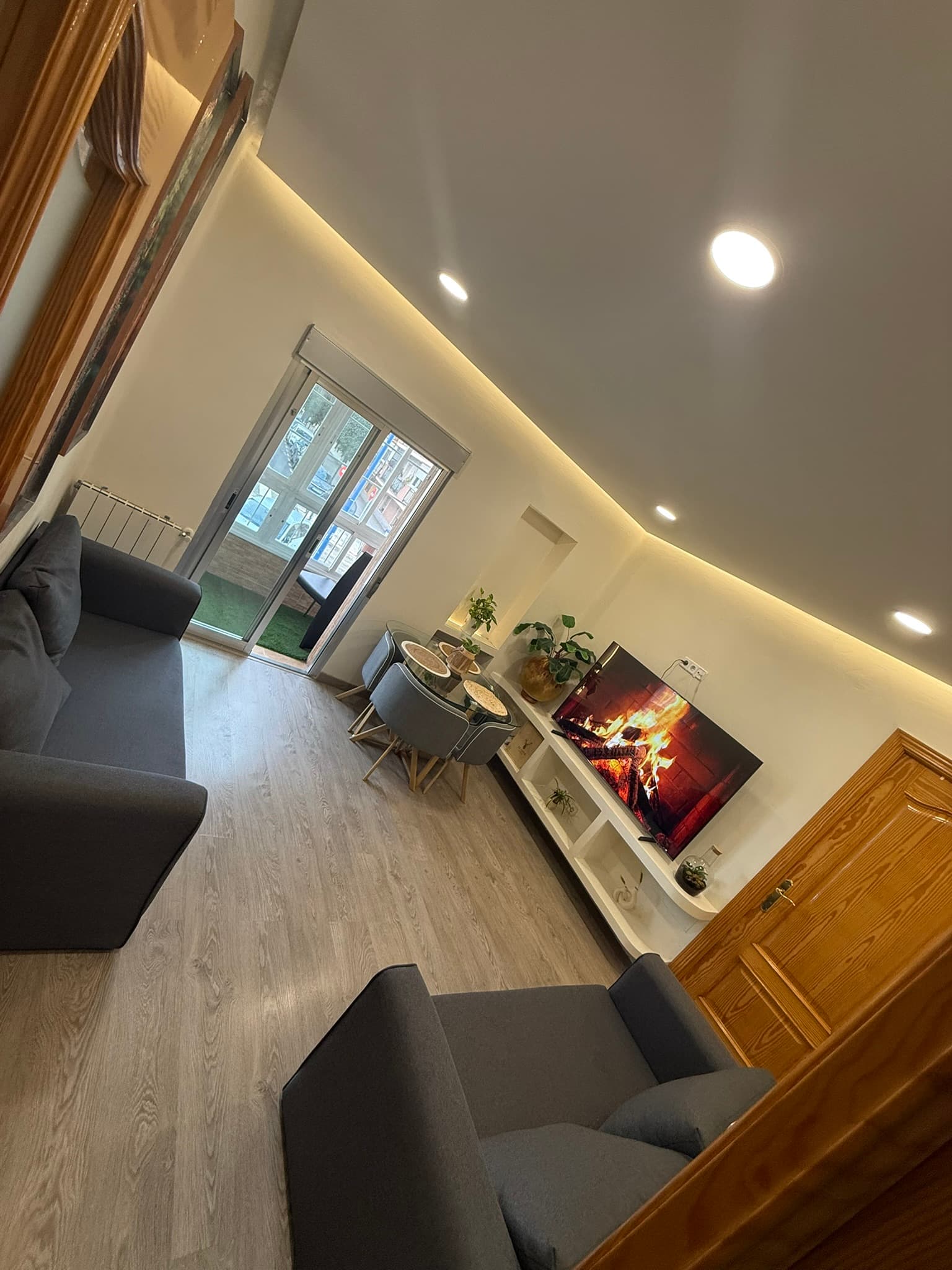 Salón con paredes en estuco blanco continuo, sofás en gris antracita e iluminación LED integrada en techo y mueble bajo