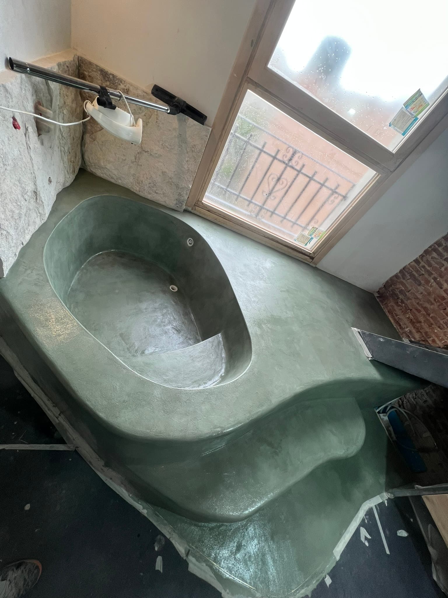 Encimera de lavabo en microcemento gris integrada en la pared, de líneas minimalistas junto a una ventana con vistas al exterior